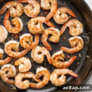 Cooked shrimp seasoned with spices in a black skillet.
