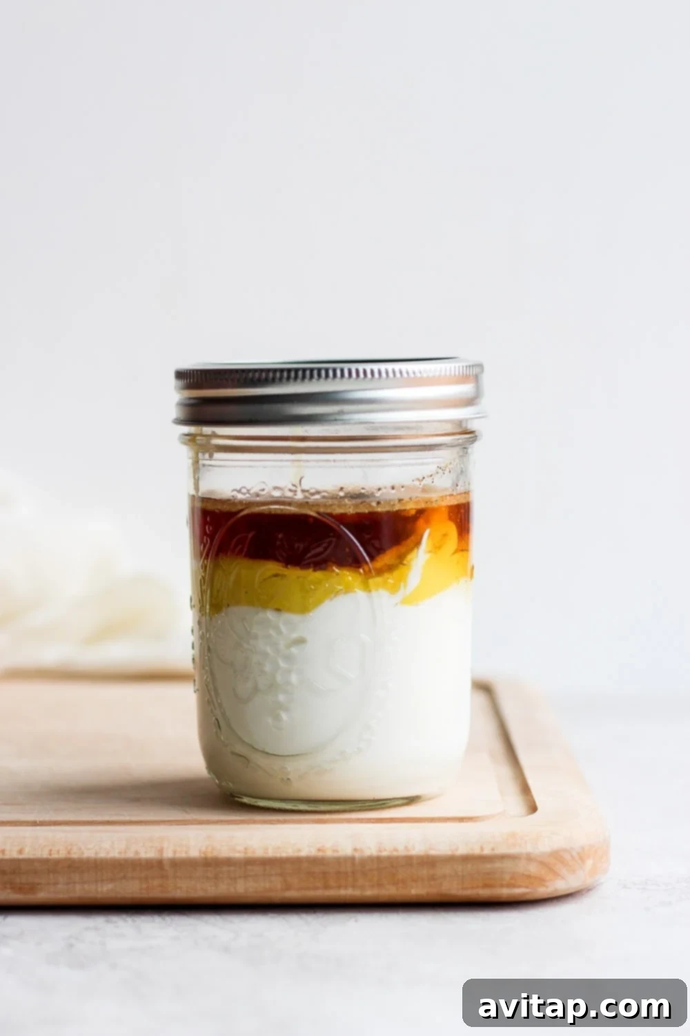 Our easy honey mustard dressing is made with just 6 ingredients and in less than 5 minutes. Bonus, it's less than 100 calories per serving! All the ingredients for honey mustard dressing stacked inside a mason jar on a cutting board