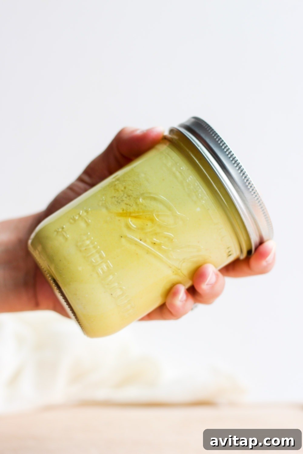 We're showing you how to make a healthy honey mustard dressing in just 5 minutes. This honey mustard dressing recipe is low fat and high protein! Hand shaking a jar of honey mustard dressing to mix the ingredients