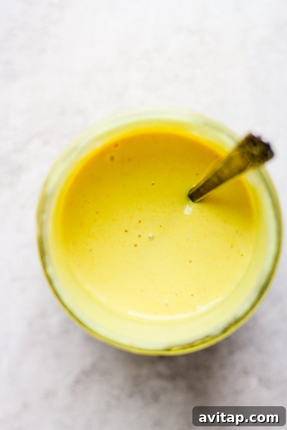Our honey mustard dressing recipe can be used as a dip or a dressing! It's thick, creamy, and healthy! A jar of thick honey mustard dressing with a spoon resting inside