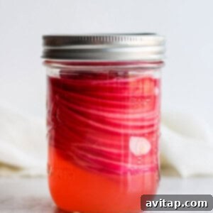 Thinly sliced red onions submerged in pickling liquid in a mason jar.