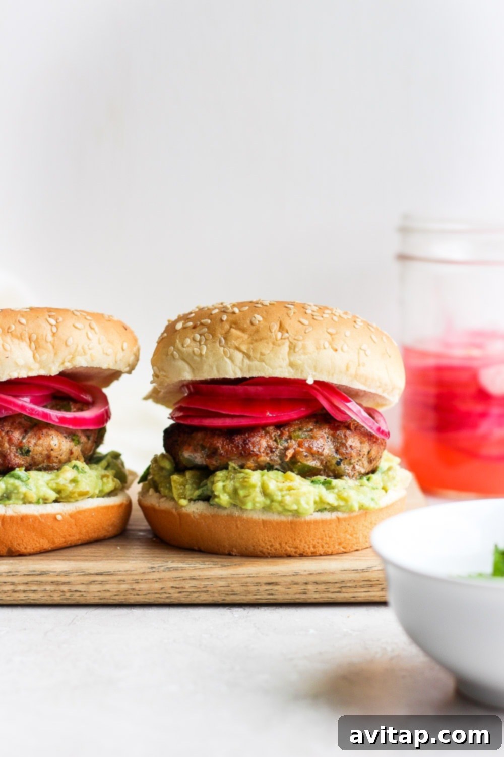 Say hello to the Best Juicy Turkey Burger you've ever had! These turkey burgers are always delicious, and never dry. Enjoy! Cooked turkey burgers served on buns with pickled onions and avocado mash, ready for a delicious meal.