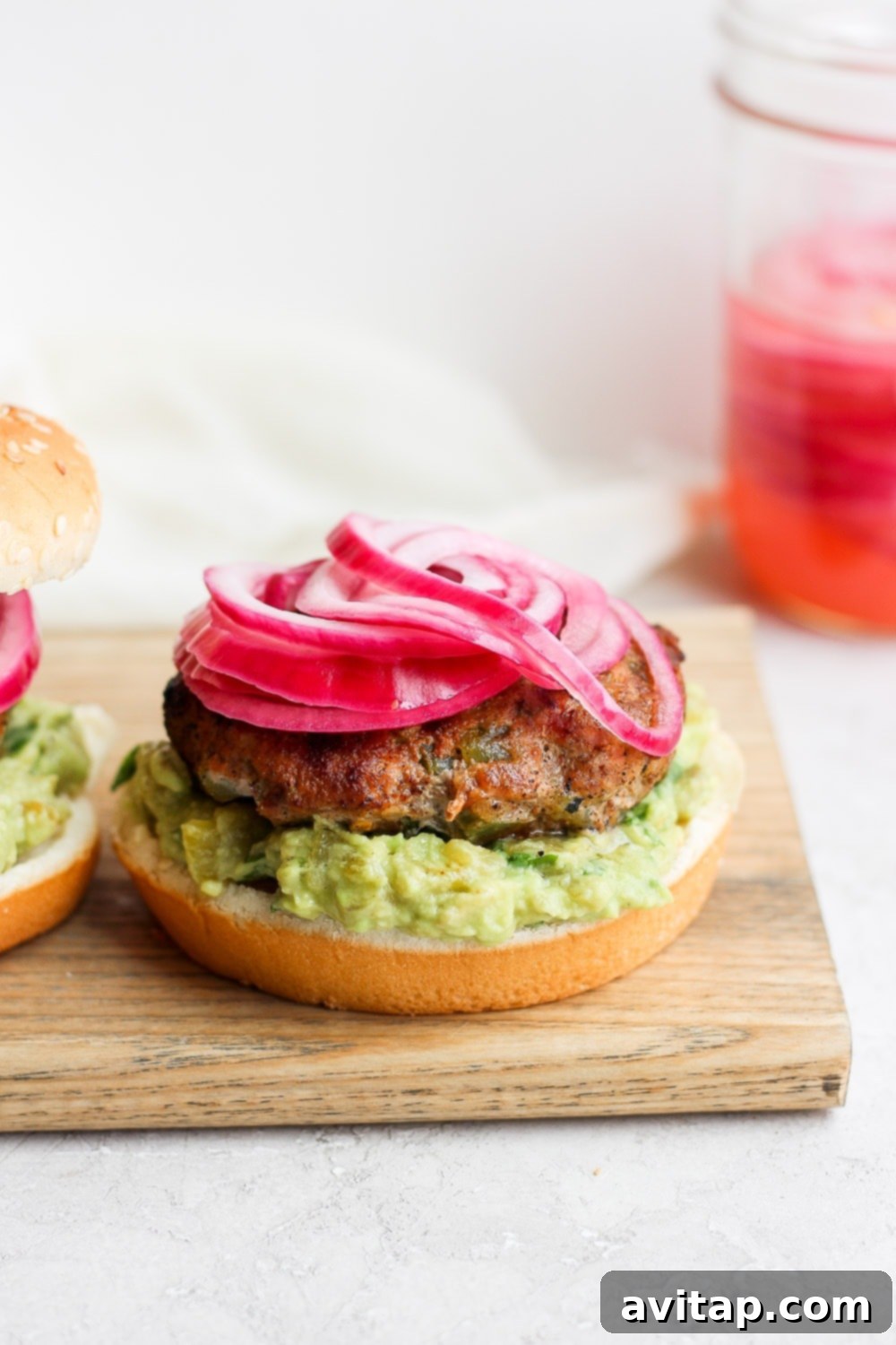 Say hello to the Best Juicy Turkey Burger you've ever had! These turkey burgers are always delicious, and never dry. Enjoy! A close-up of a juicy turkey burger topped with bright pickled onions, emphasizing its delicious appeal.