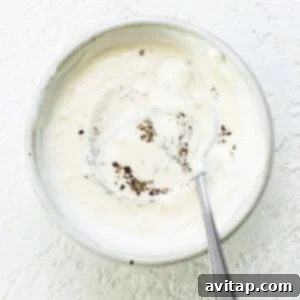 A bowl of creamy aioli sauce with a spoon.