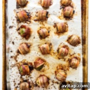Bacon-wrapped Brussels sprouts baking on a sheet in the oven.