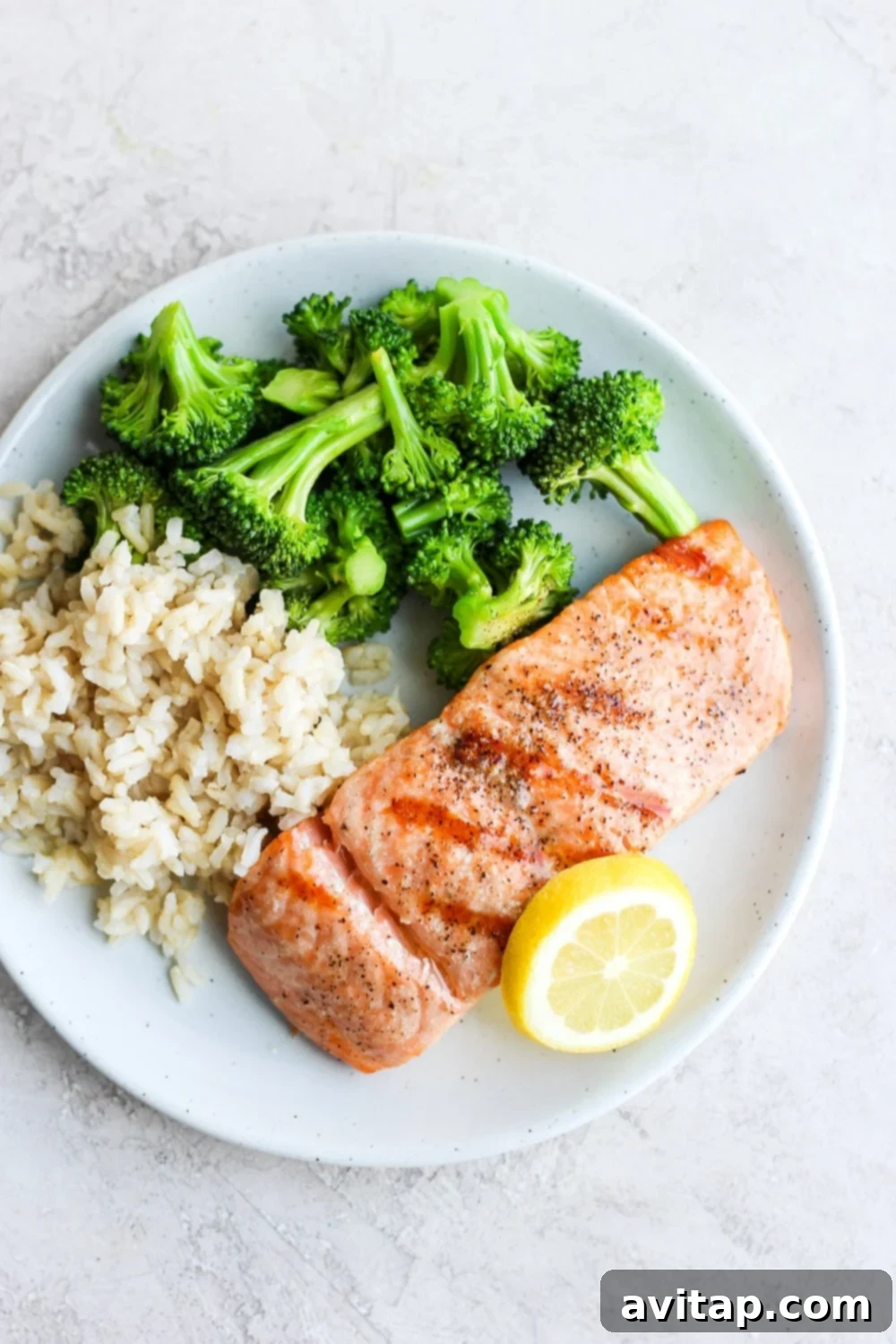 A beautifully grilled salmon fillet served on a plate with fresh broccoli and fluffy rice, showcasing a perfect meal.