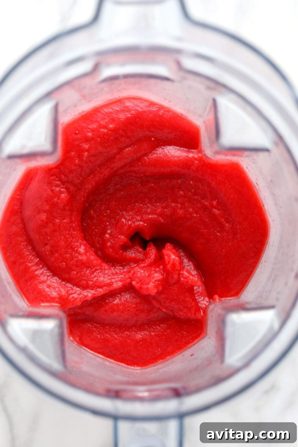 Blend up your own strawberry daiquiri recipe at home for the most delicious frozen drink ever! And bonus: this drink recipe has NO refined sugar! Freshly blended strawberry daiquiris in a high-speed blender, showcasing a smooth, thick consistency, ready to be poured.