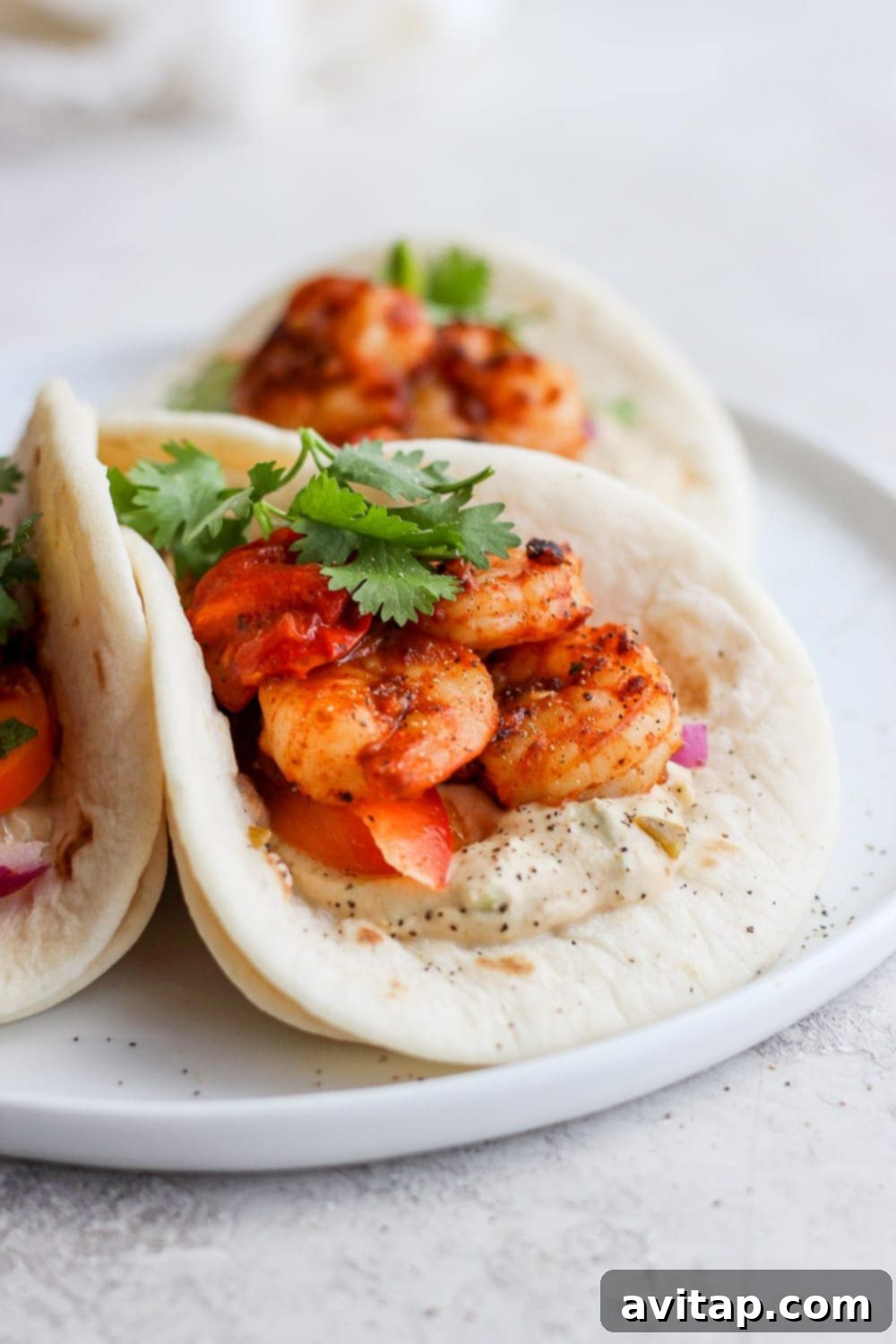 Three perfectly assembled shrimp tacos in street taco tortillas, showcasing all the delicious fillings