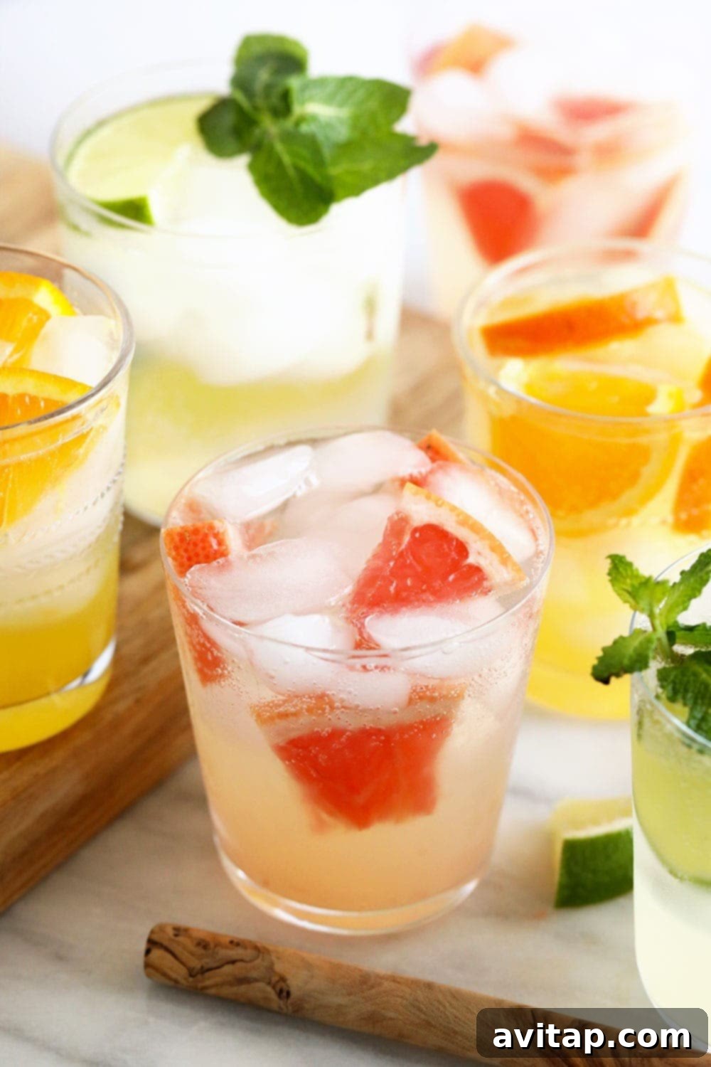 A collection of freshly prepared homemade hard seltzers in elegant glasses, garnished with citrus and mint.