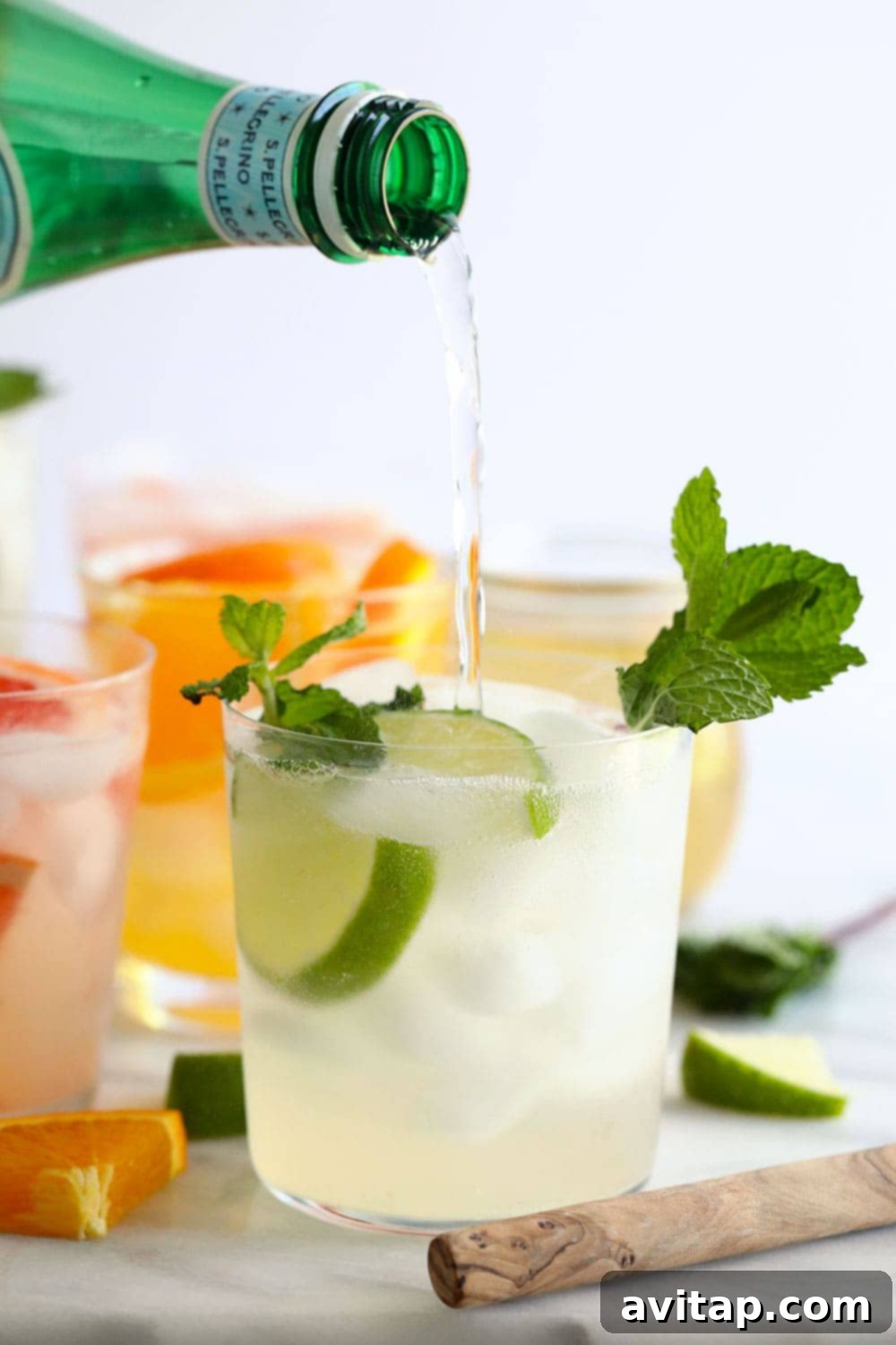 A hand carefully pouring effervescent sparkling water into a glass of hard seltzer, creating a refreshing fizz.