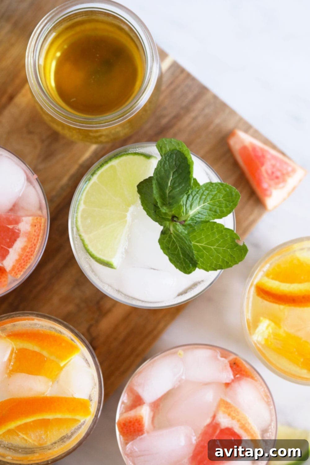 Three different flavors of homemade hard seltzers, each in a unique glass and garnished, ready for serving.