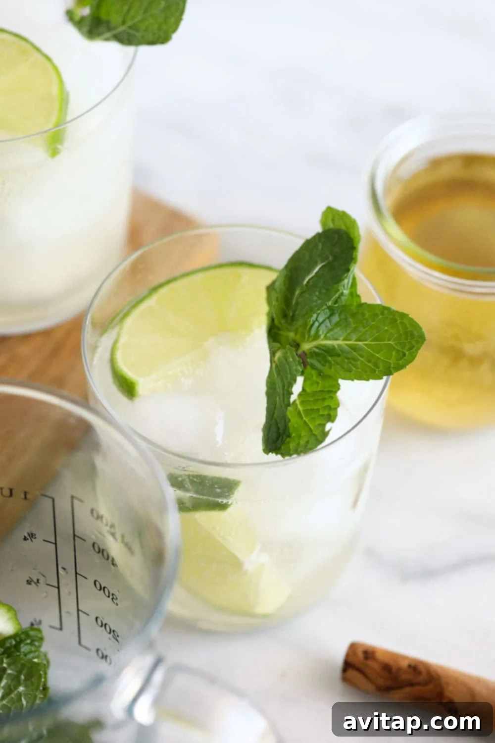 A clear glass filled with a vibrant green lime and mint hard seltzer, garnished with fresh mint leaves and lime wedges.