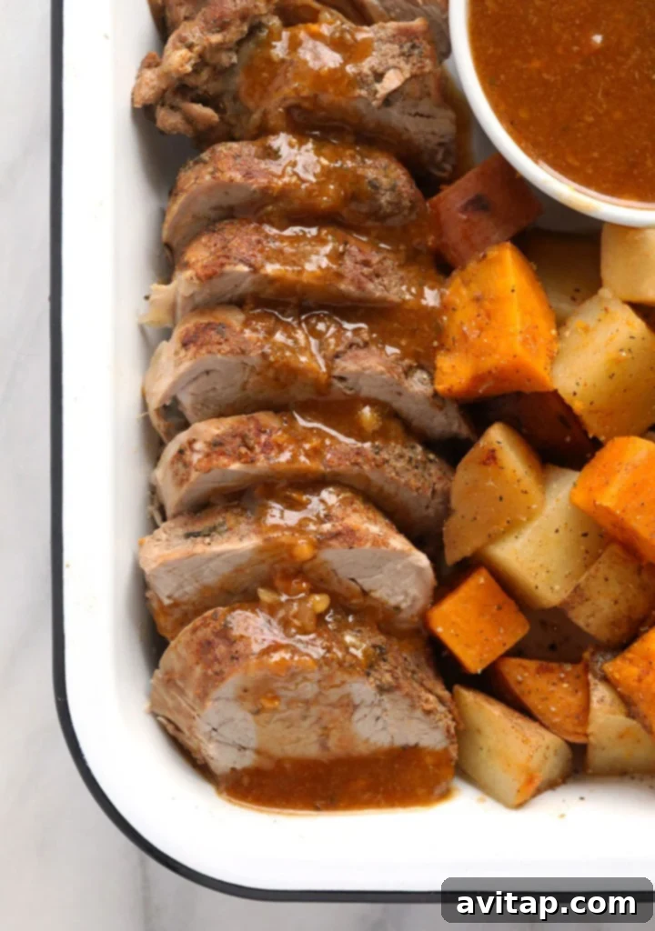 Instant pot pork tenderloin on a platter, garnished with fresh herbs and served with gravy and potatoes.