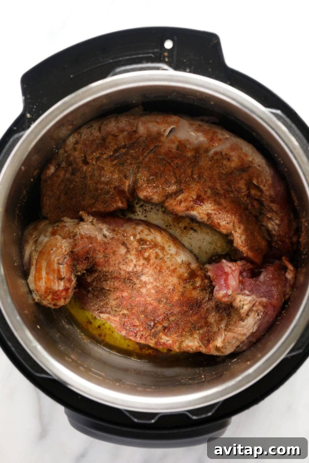 Pork tenderloin being seared in the Instant Pot before pressure cooking.