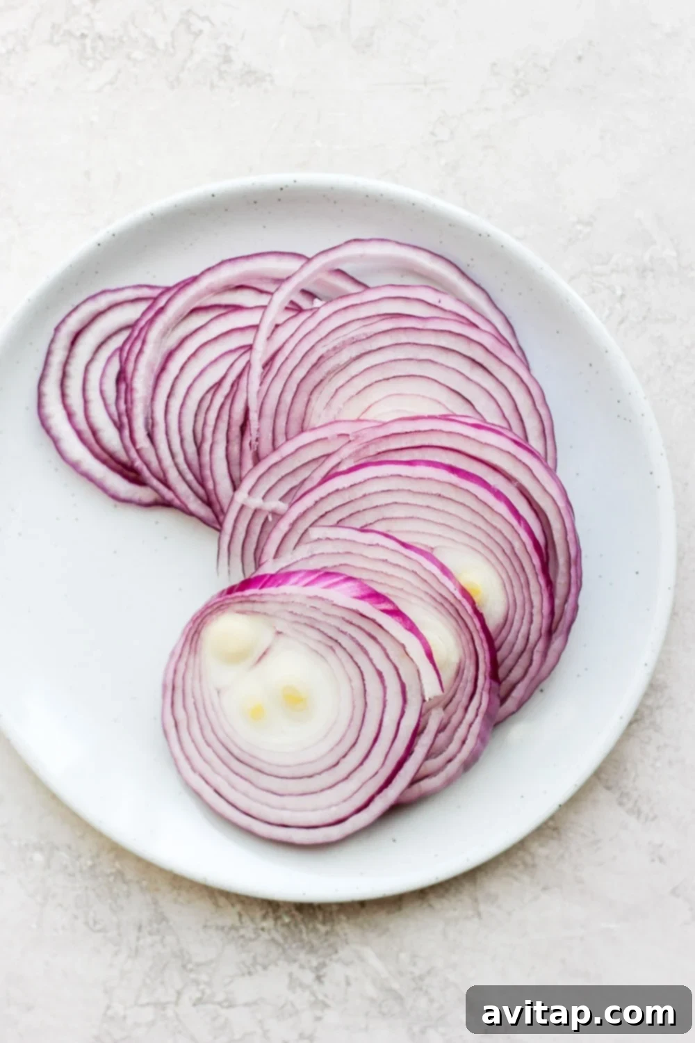 Thinly Sliced Raw Red Onions for Pickling Fresh, raw red onions thinly sliced on a cutting board, ready for pickling