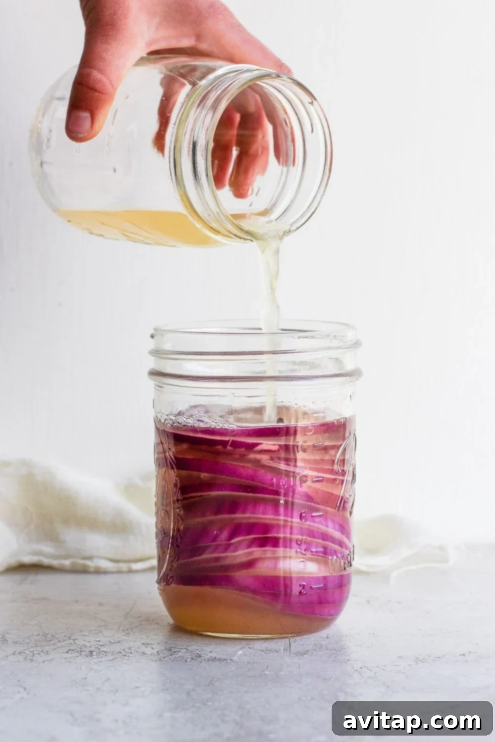 Pouring Brine Over Onions for Pickling Hand pouring pickling vinegar over sliced red onions in a glass jar