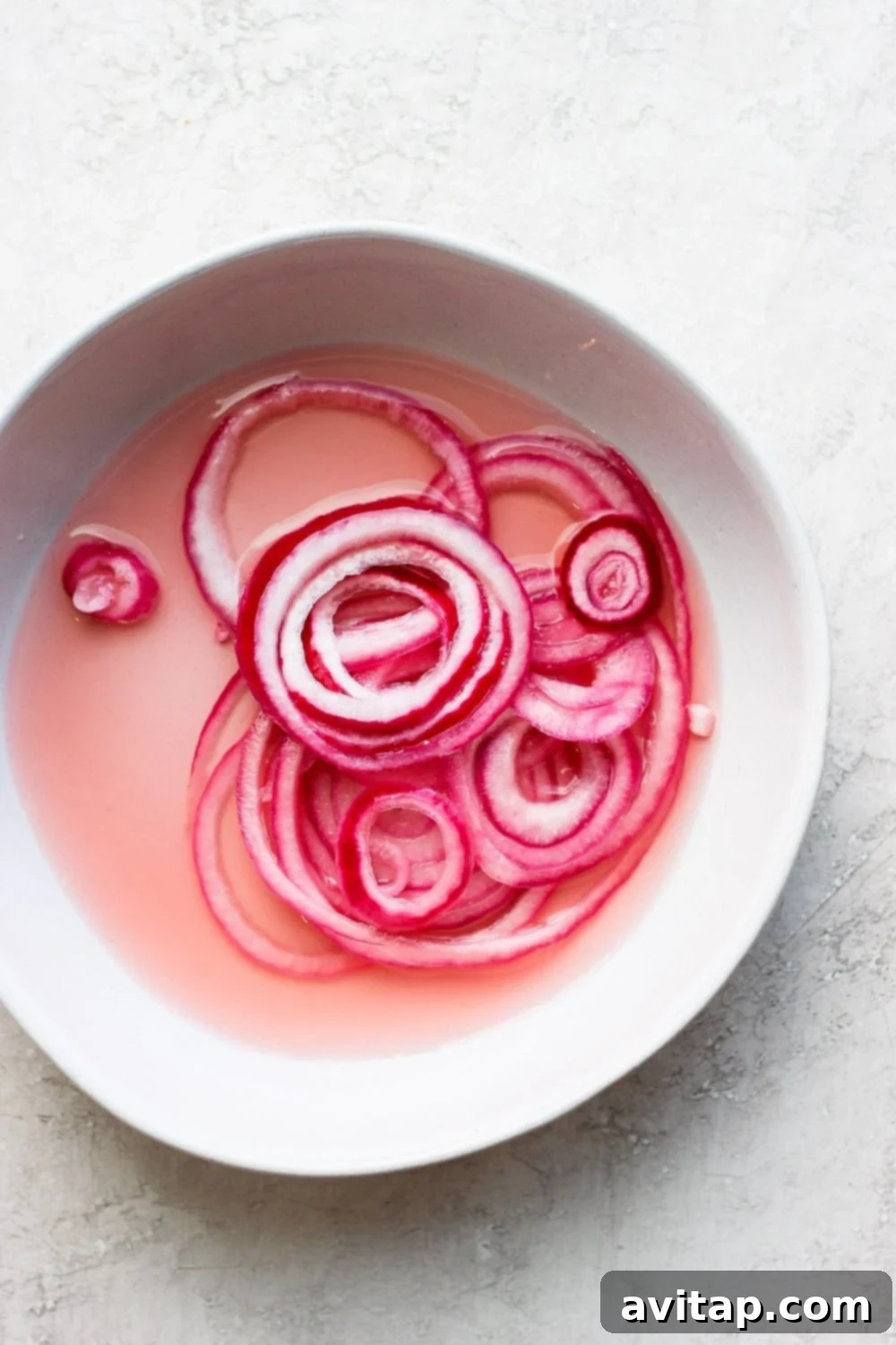 Bowl of Vibrant Quick Pickled Red Onions Bowl of quick pickled red onions on a white surface, ready to be served