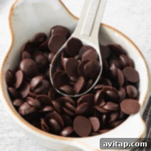 A close-up of homemade vegan chocolate chips in a white bowl, ready to be enjoyed or used in baking.
