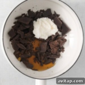 A bowl filled with a smooth, melted chocolate mixture and a whisk, ready for the next step in making vegan chocolate chips.