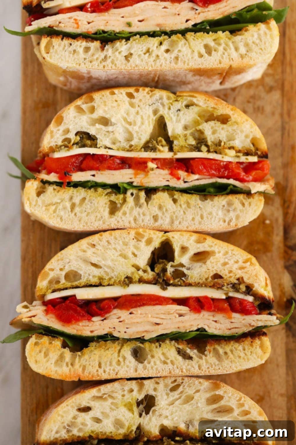 Grilled Roasted Red Pepper, Pesto & Turkey Sandwich on a cutting board
