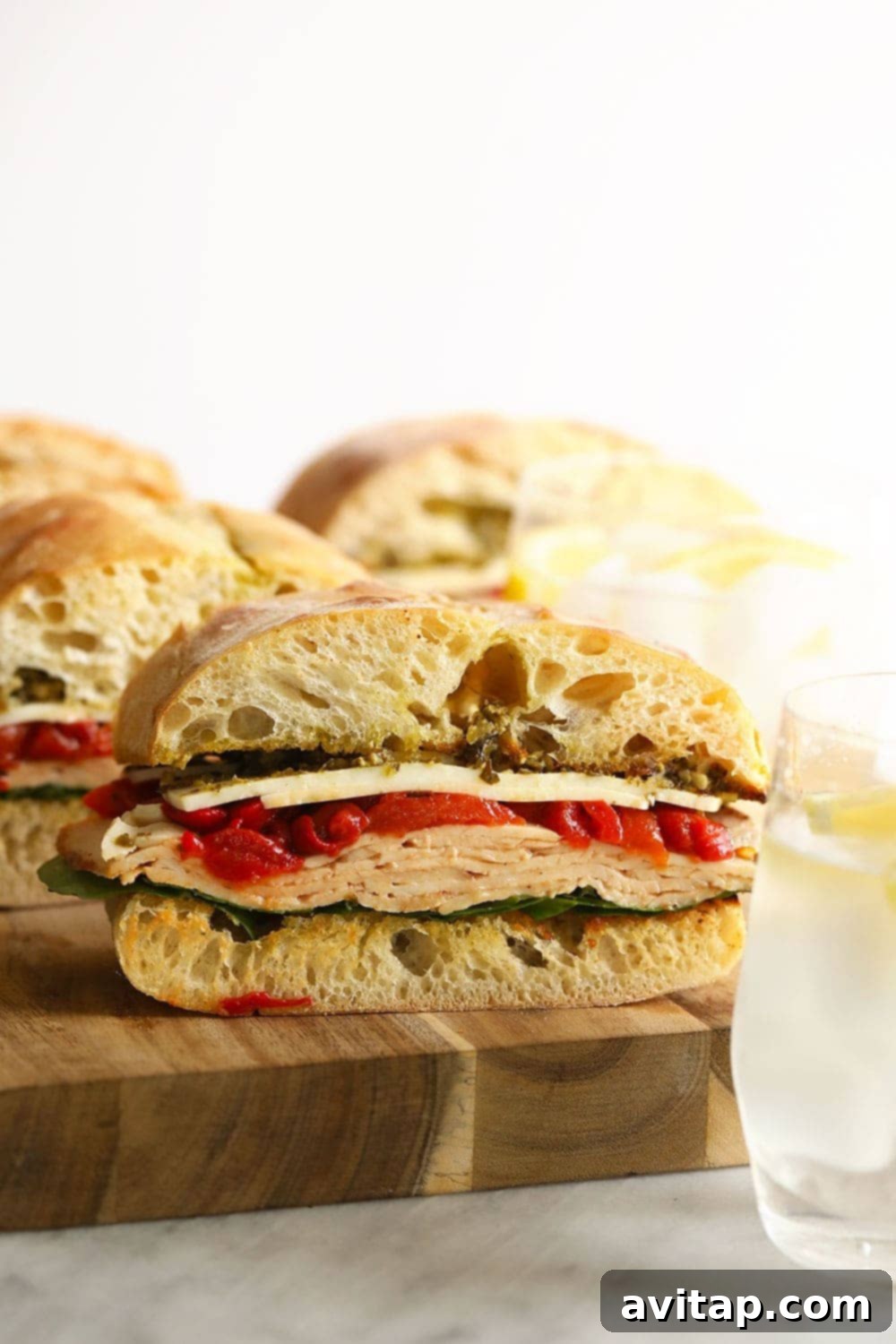 A single portion of the grilled turkey pesto sandwich on a cutting board, garnished with fresh herbs