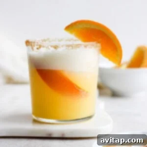 An orange cocktail garnished with a slice of orange.
