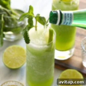 A vibrant green frozen mojito, garnished with fresh mint and lime, showcasing its refreshing appeal.