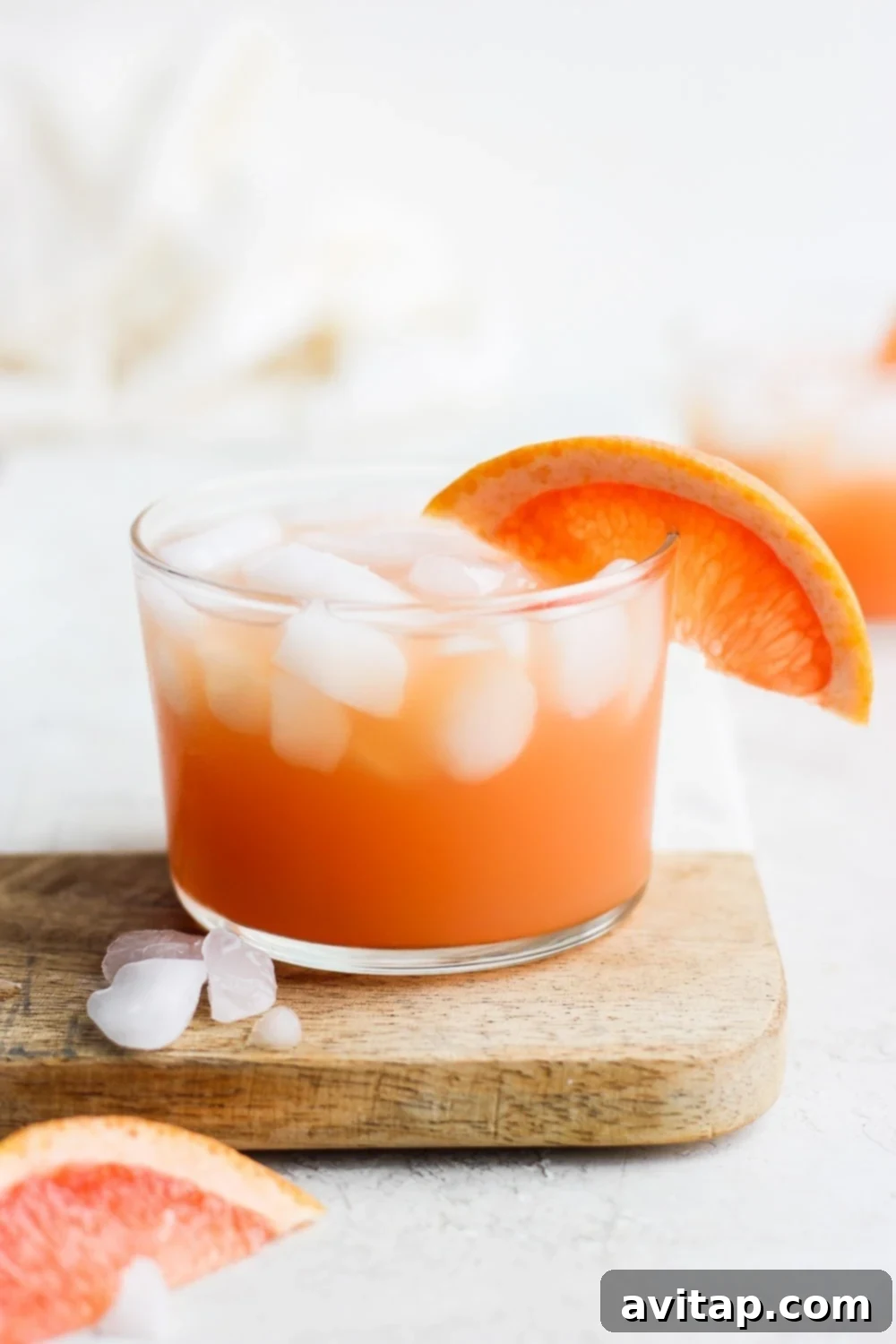 A vibrant Paloma cocktail, garnished with a fresh grapefruit slice on the rim, showcasing its inviting pink hue and ice-cold appeal