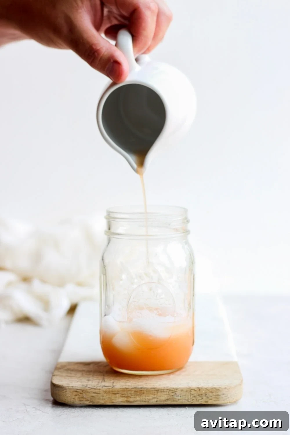 Freshly squeezed grapefruit juice being poured into a mason jar, a key ingredient for the perfect homemade Paloma cocktail