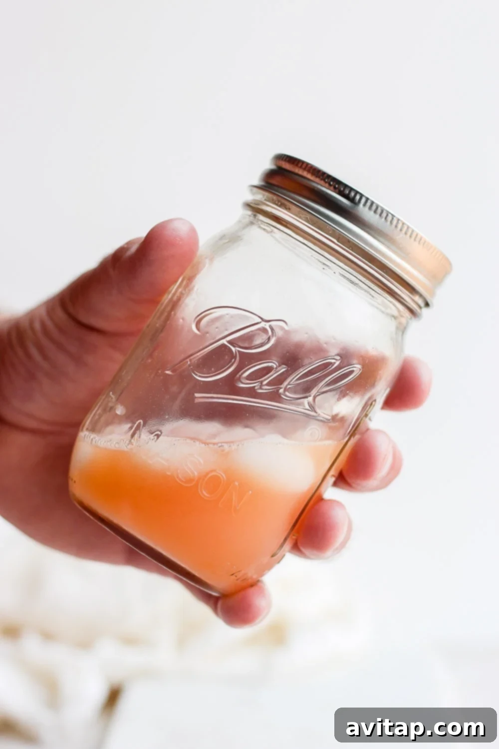 A refreshing Paloma cocktail served in a stylish mason jar, filled with ice and a bright slice of grapefruit