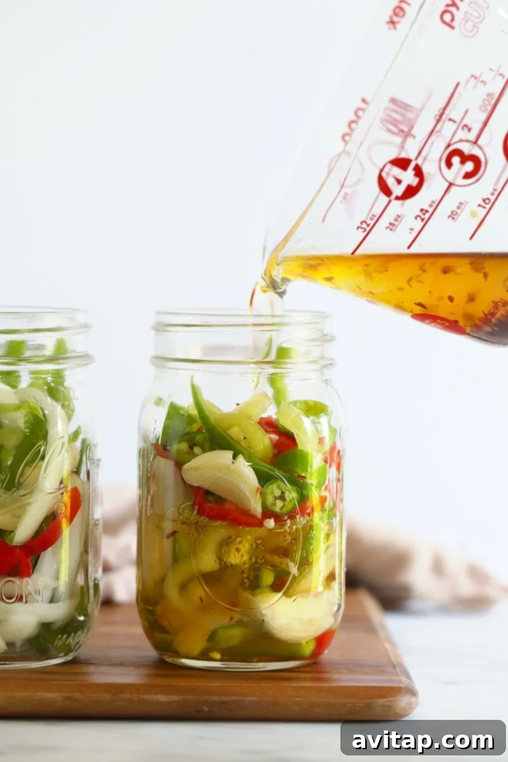 Assortment of sliced peppers nestled in a mason jar, submerged in pickling brine.