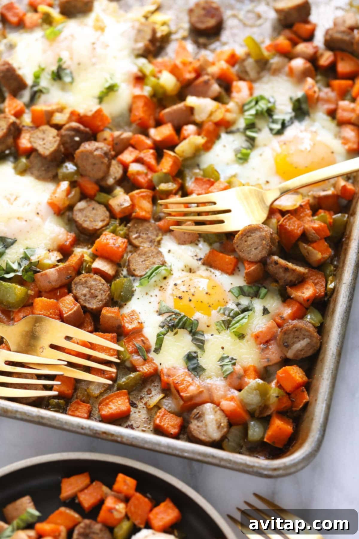 Sweet potato hash on a baking sheet with two forks, ready to be shared.