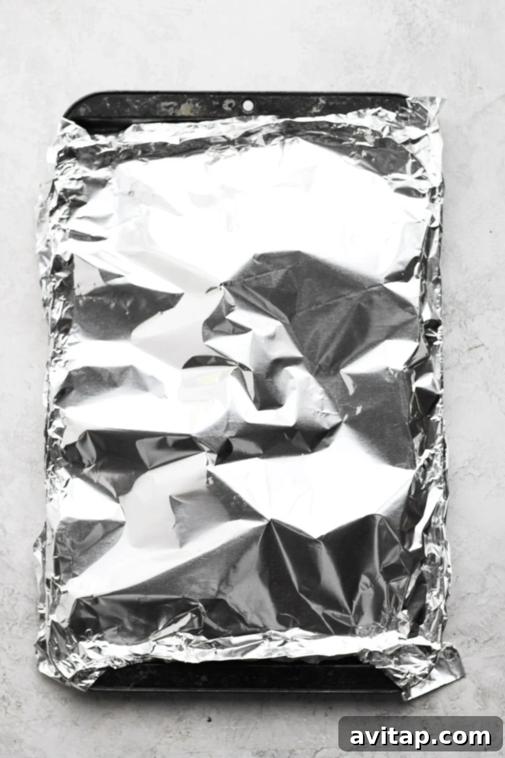 Baked salmon, expertly covered in aluminum foil on a baking sheet, preserving its moisture and flavor during the cooking process.