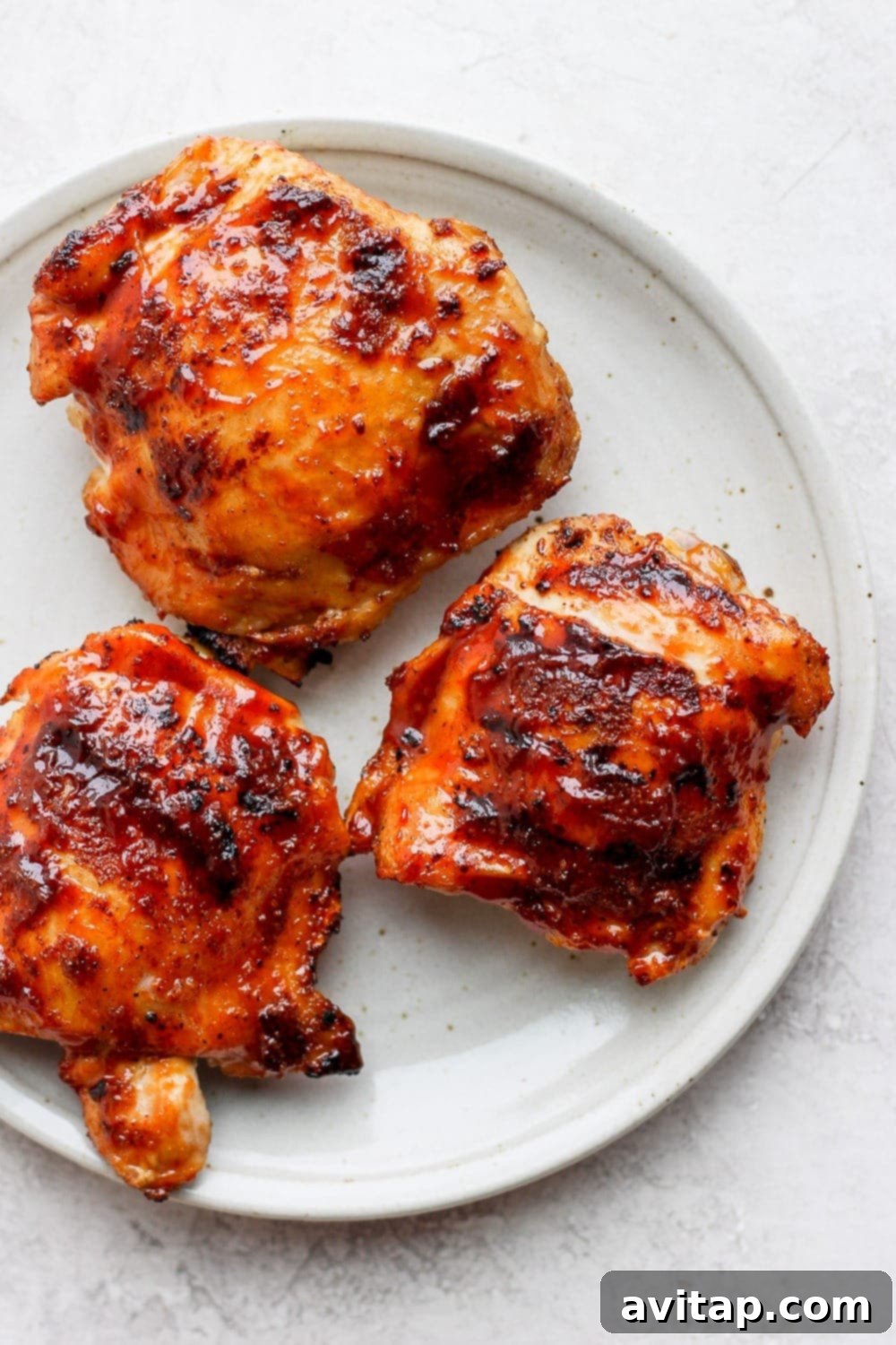 The Best Grilled BBQ Chicken Thighs: Crispy Skin & Juicy Meat Grilled chicken thighs on a plate, showcasing crispy skin and juicy meat.