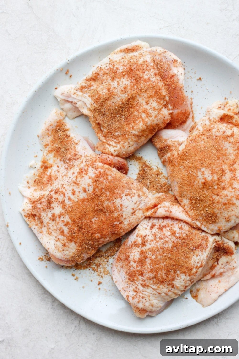 Preparing Chicken Thighs for Grilling Uncooked chicken thighs on a plate, showcasing their readiness for seasoning.