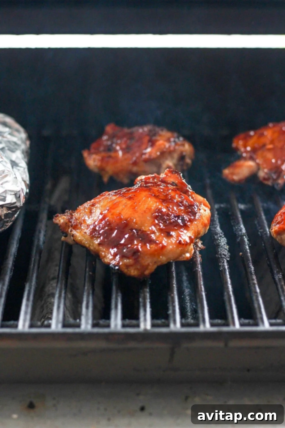 Grilling BBQ Chicken Thighs to Perfection Chicken thighs sizzling on the grill grates, skin side down.