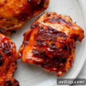 Smoky Grilled BBQ Chicken Thighs 3 Three grilled chicken thighs on a plate, looking delicious.