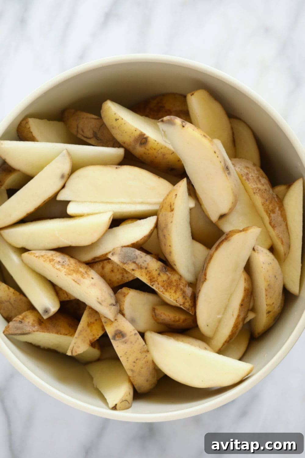 Chopped potato wedges in a bowl, ready for seasoning.