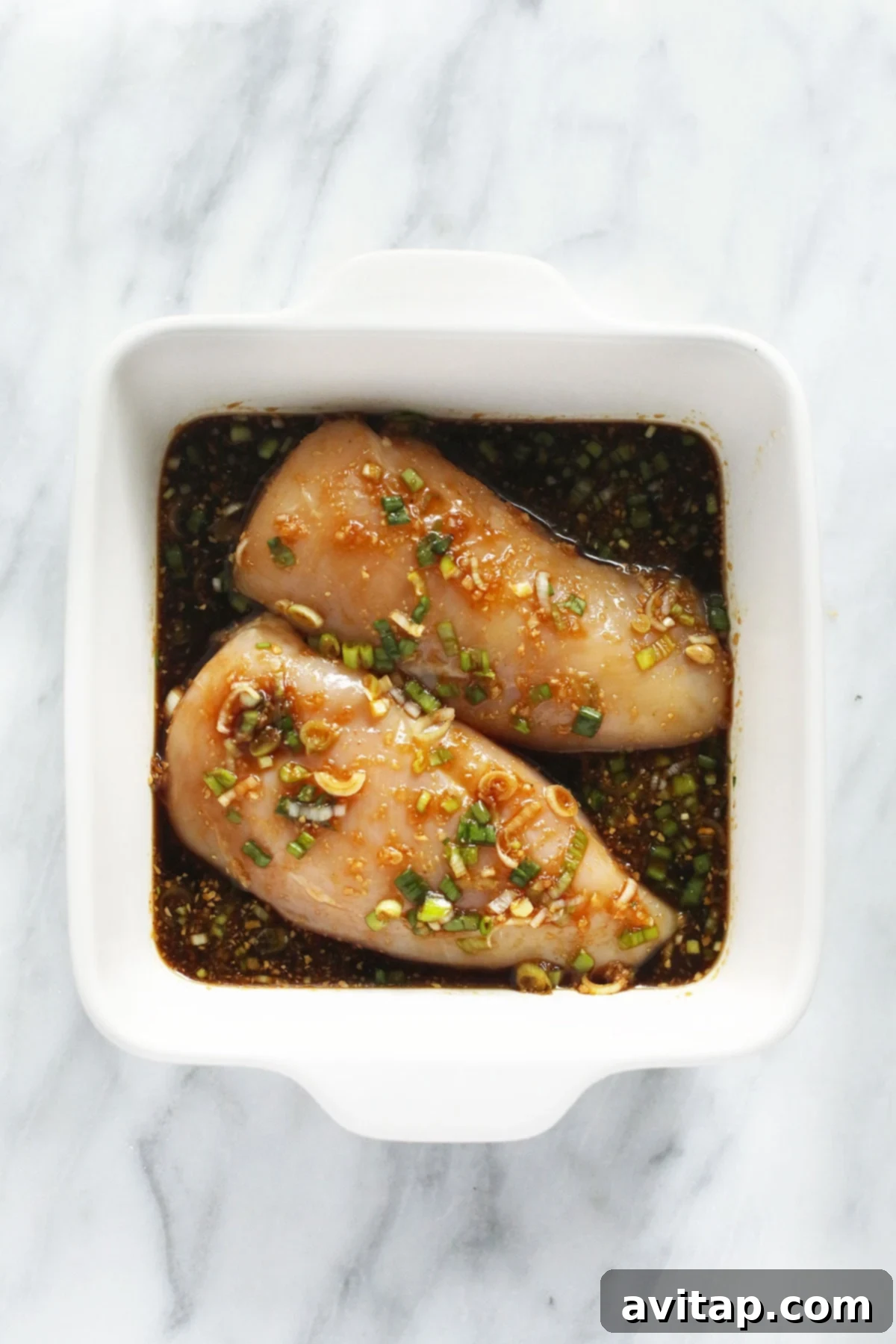 Teriyaki chicken marinating, absorbing rich flavors. Chicken breasts soaking in a vibrant teriyaki marinade inside a glass dish, ready for cooking.