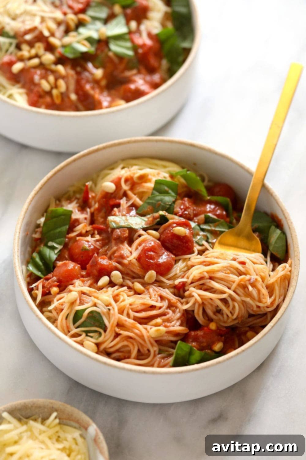 Two bowls of vibrant garden summer pasta garnished with fresh basil leaves, ready to be enjoyed.