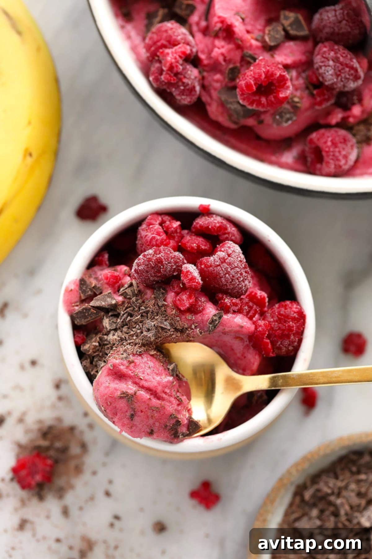 A beautifully presented bowl of Raspberry Chocolate Chunk Nice Cream, ready to be savored, garnished with fresh raspberries and extra chocolate chunks.