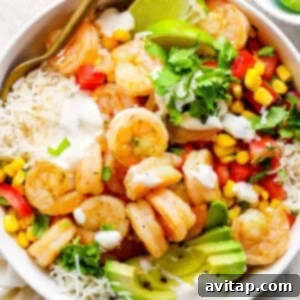Cilantro Lime Rice Two Ways 2 A white bowl with shrimp, cilantro lime rice, and colorful vegetables, topped with a creamy sauce.