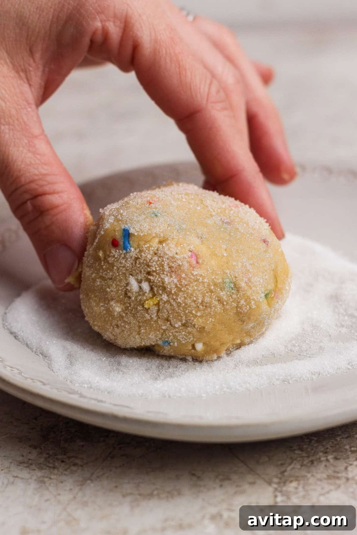 Rolling cookie dough in sugar and sprinkles.