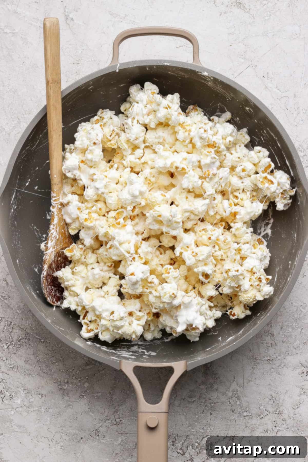 Popcorn coated in a white marshmallow mixture in a pan.