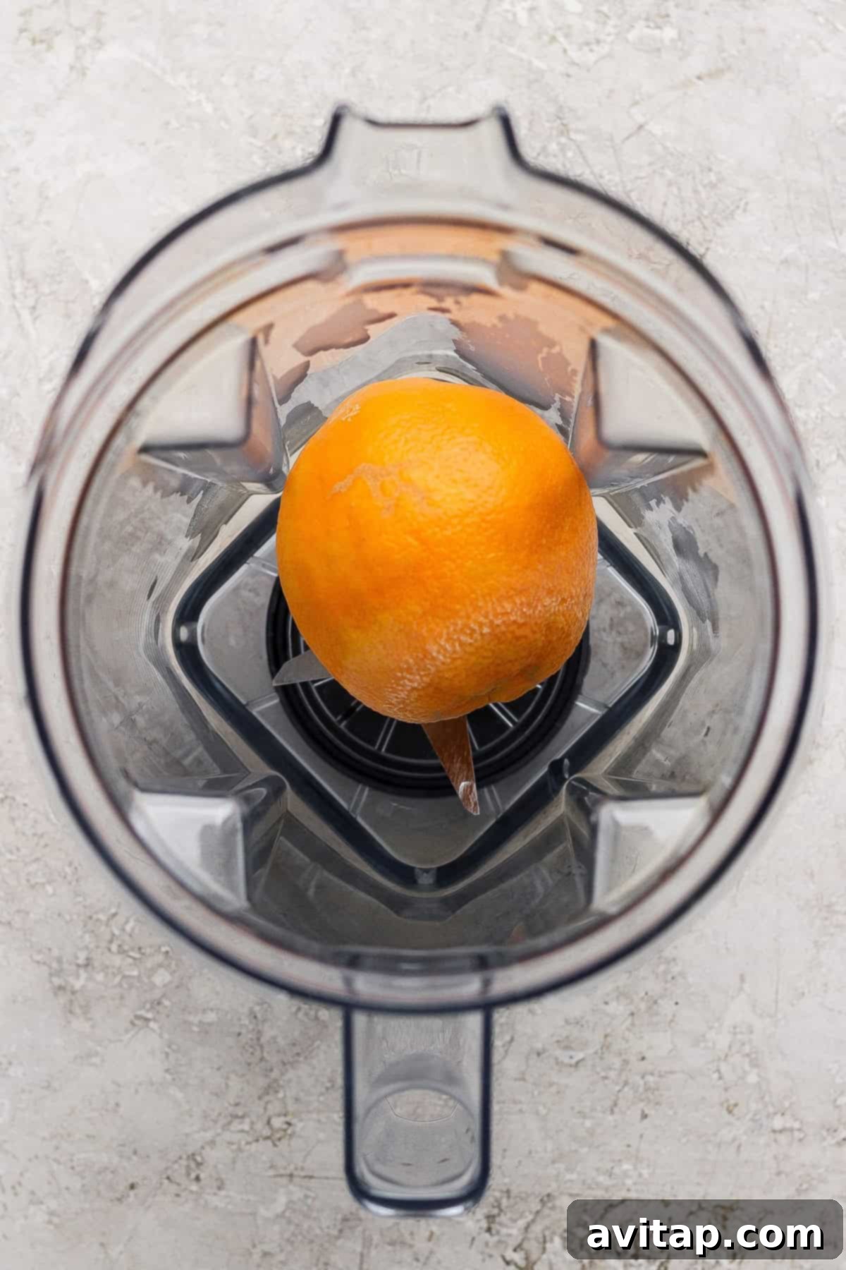 A whole orange being prepared for blending.