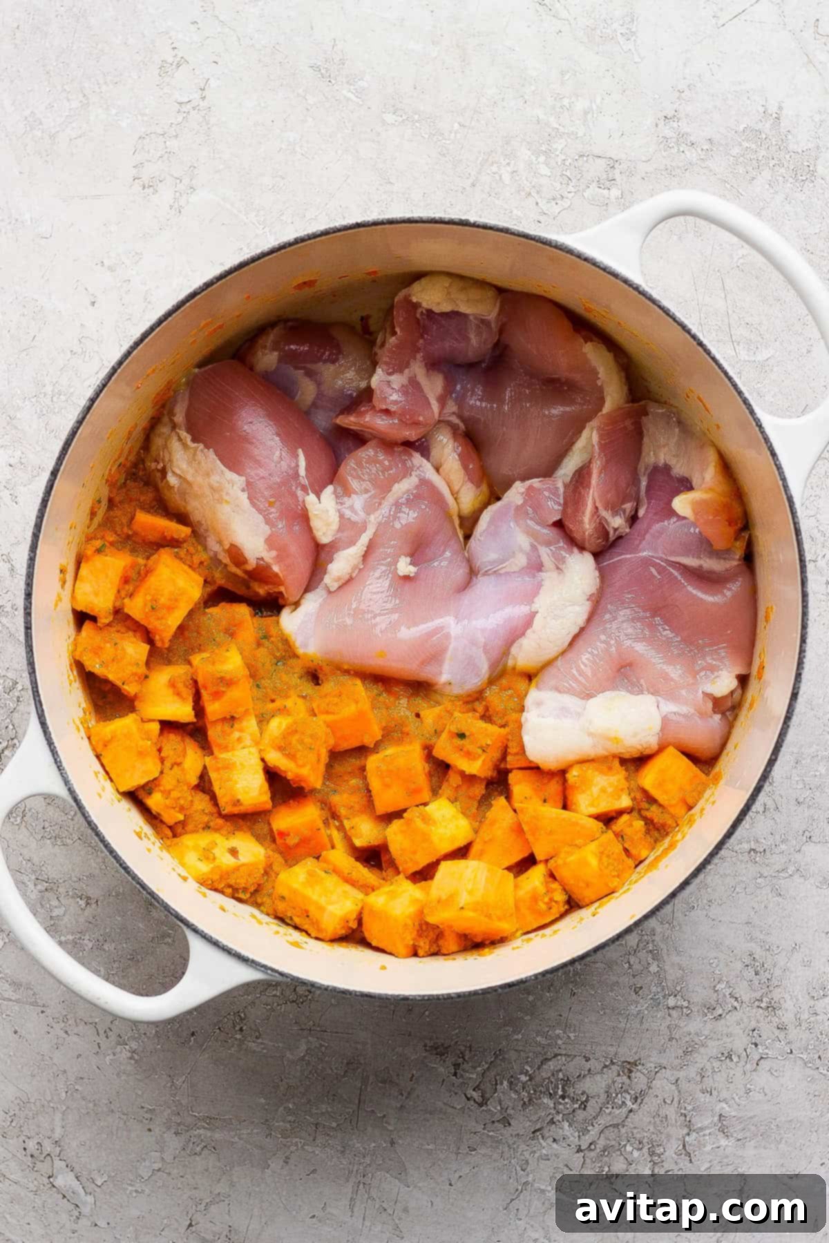 Chicken thighs and sweet potatoes in a pot.