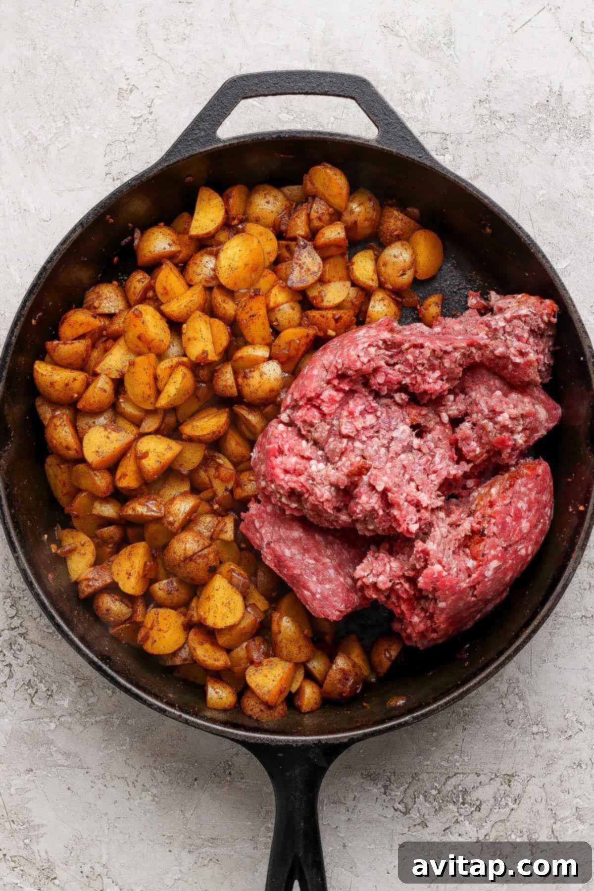 Ground beef and potatoes cooking separately in a skillet.