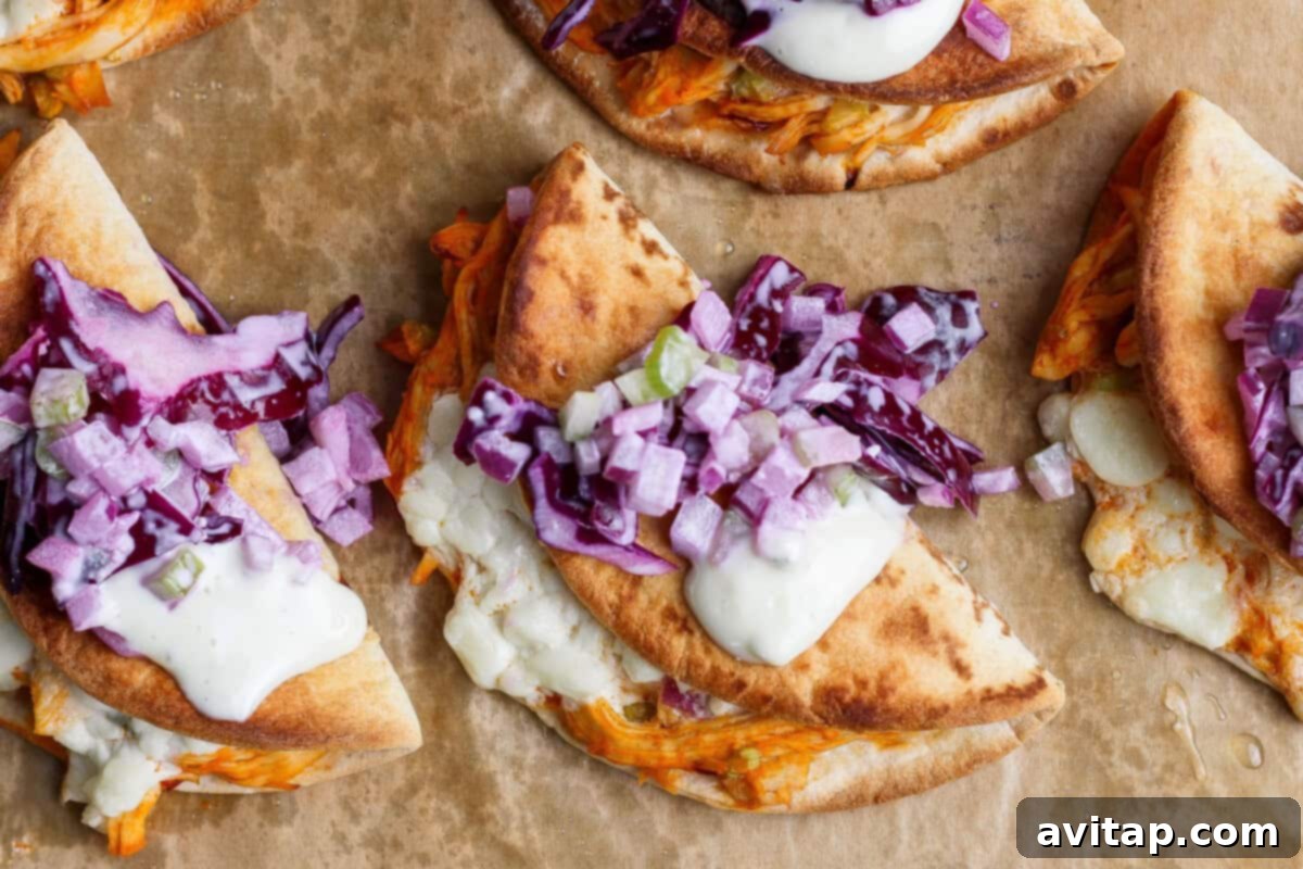 Sheet Pan Buffalo Chicken Tacos - Crispy flatbreads filled with shredded chicken, cheese, buffalo sauce, red onions, and cabbage.
