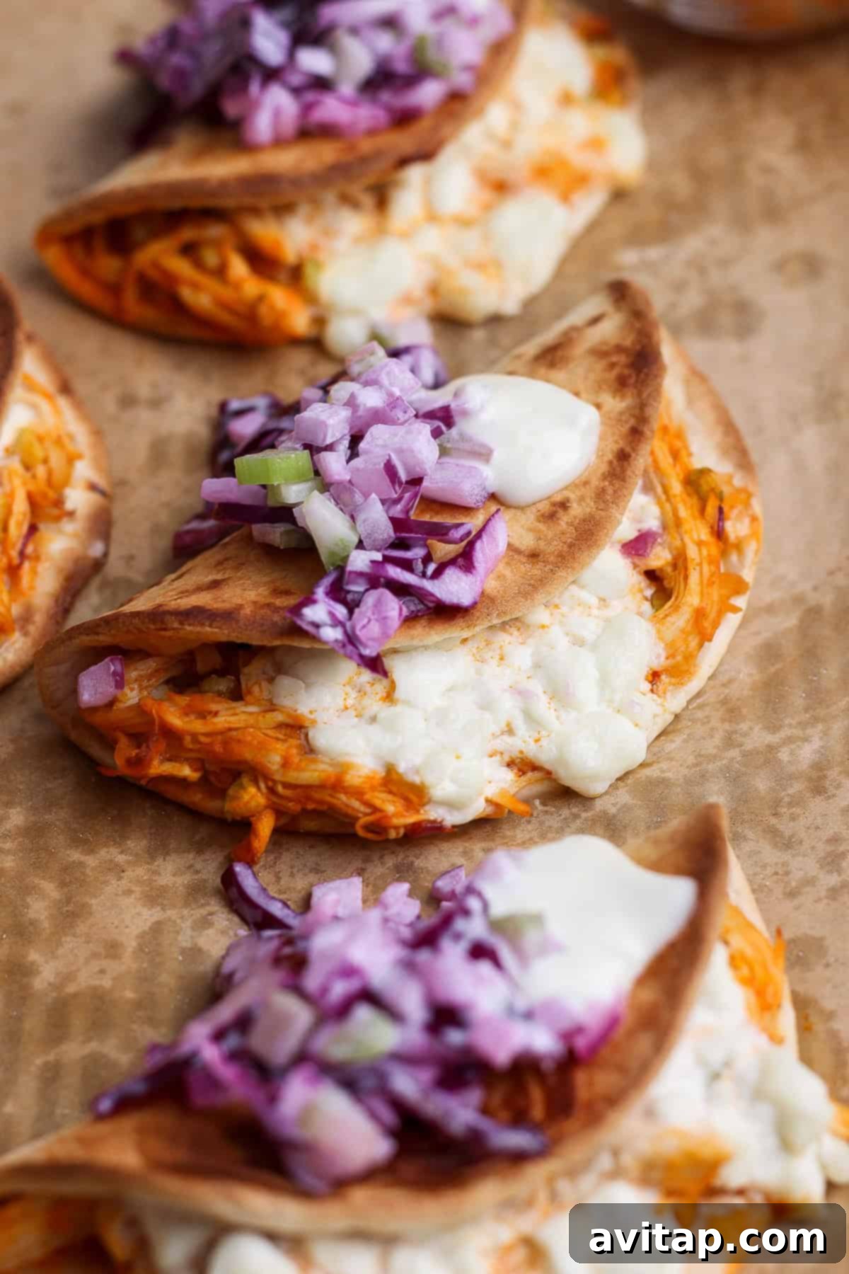 Close-up of Buffalo Chicken Tacos - Crispy tacos with melted cheese, red onions, and buffalo sauce.