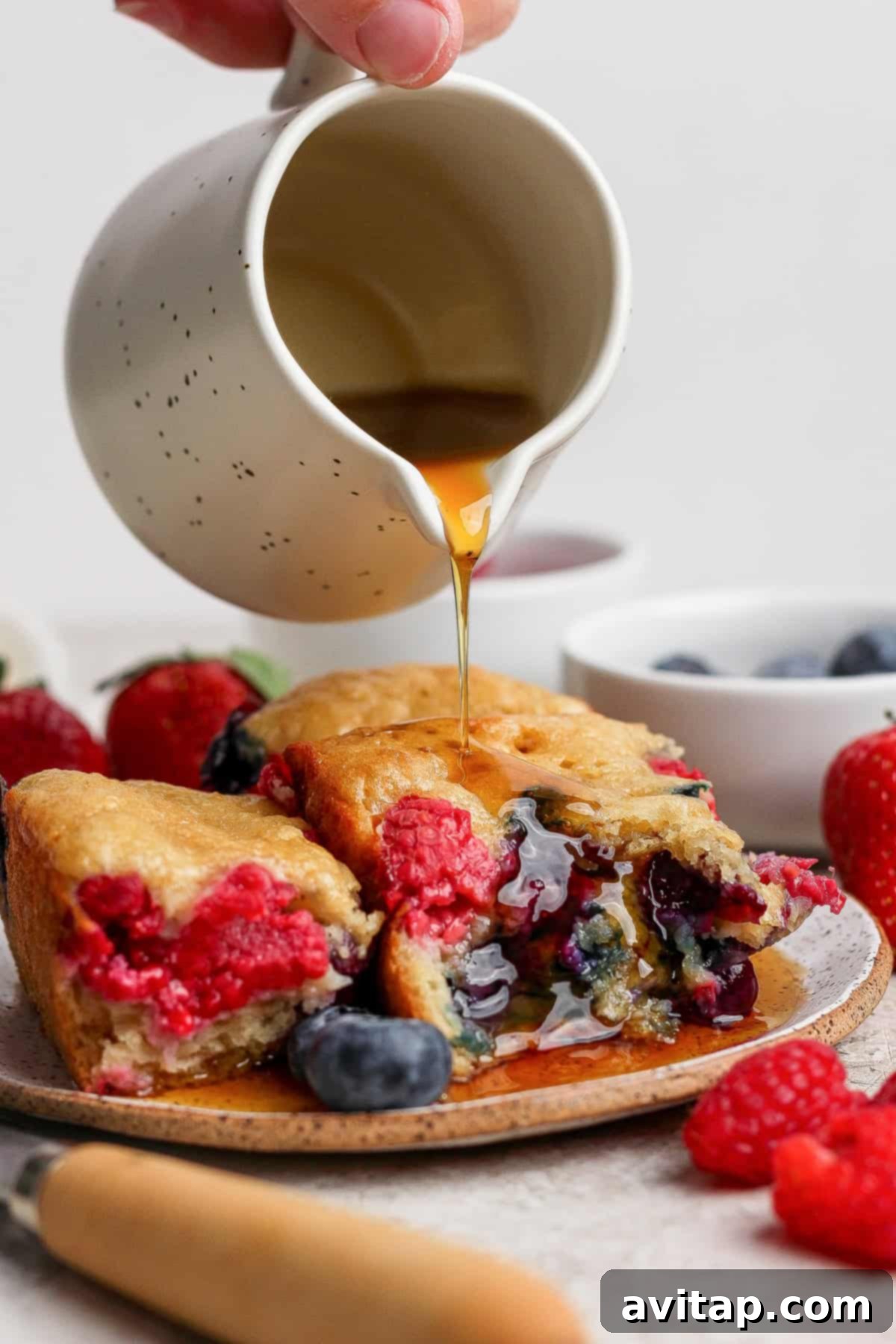 Stack of High Protein Triple Berry Buns drizzled with maple syrup